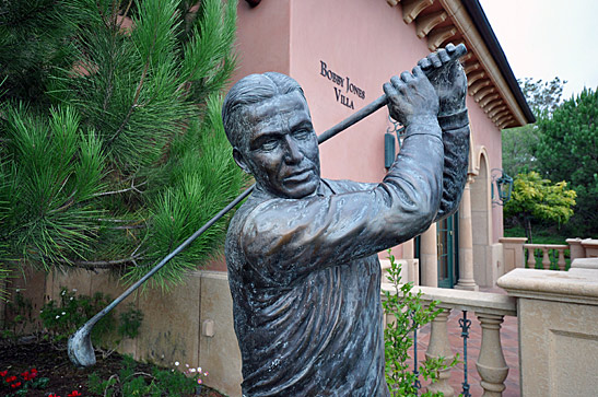 a statue of golfer Bobby Jones with a villa named after him in the background