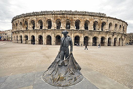 statue of bullfighter Nimeño II with Roman amphitheater in the background, Nîmes