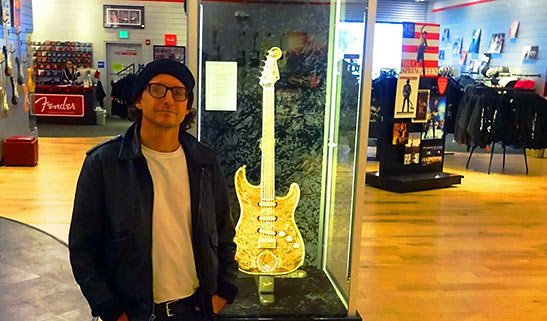 writer with rare guitar covered in jewels on display at the Fender Visitor Center