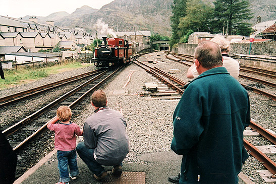 boy with dad and elder couple watching incoming steam train