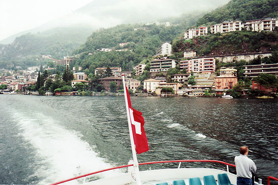 View of lakeside town and mountains from a boat with a Swiss flag