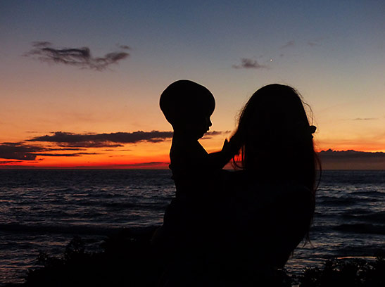 sunset scene: mother and son on the beach