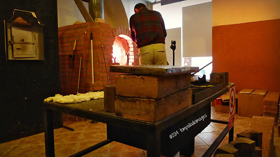 artisan glassblower at work in front of a furnace