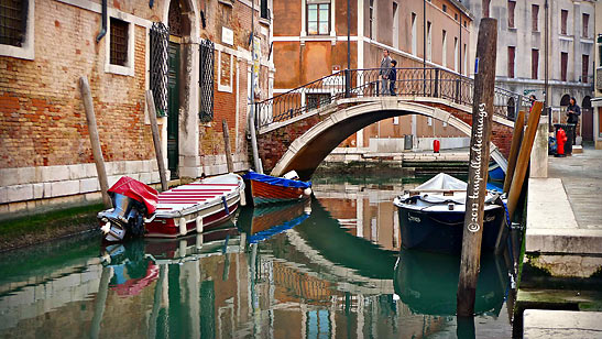 gondolas docked beside an arched bridge over a waterway