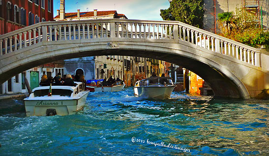 boats passing under an arched bridge at one of Venice's 150 canals