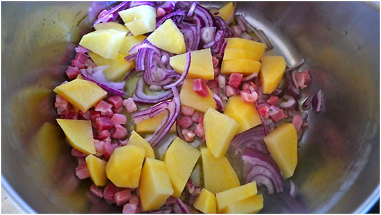 bacon cubes, chopped red onion and cubed potatoes in a bowl