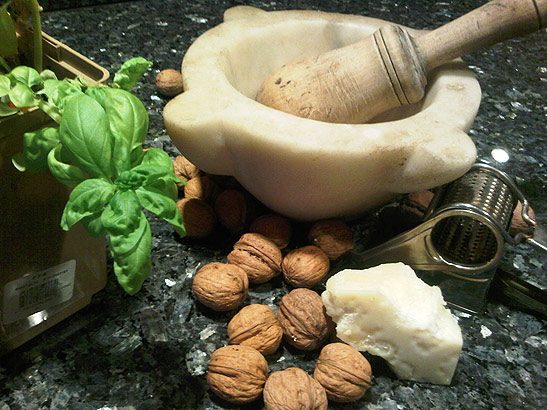 cooking utensils with walnuts, basil leaves and cheese