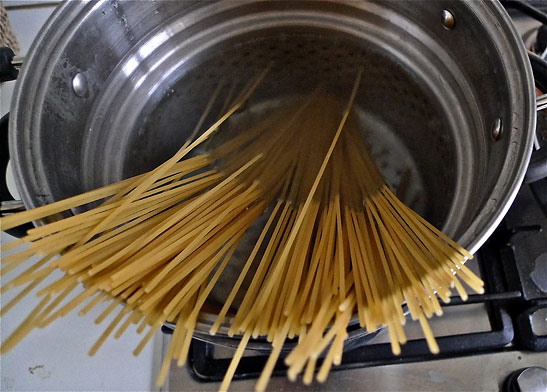 spaghetti dropped into large pasta pot