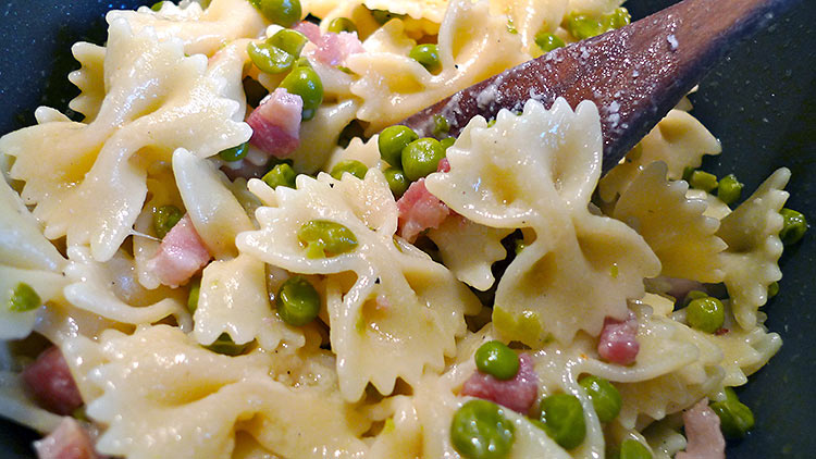 farfalle pasta added to peas and pancetta