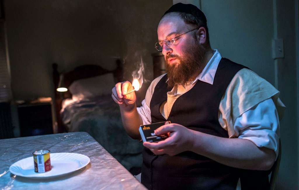 Menashe Lustig lights a memorial candle for his deceased wife