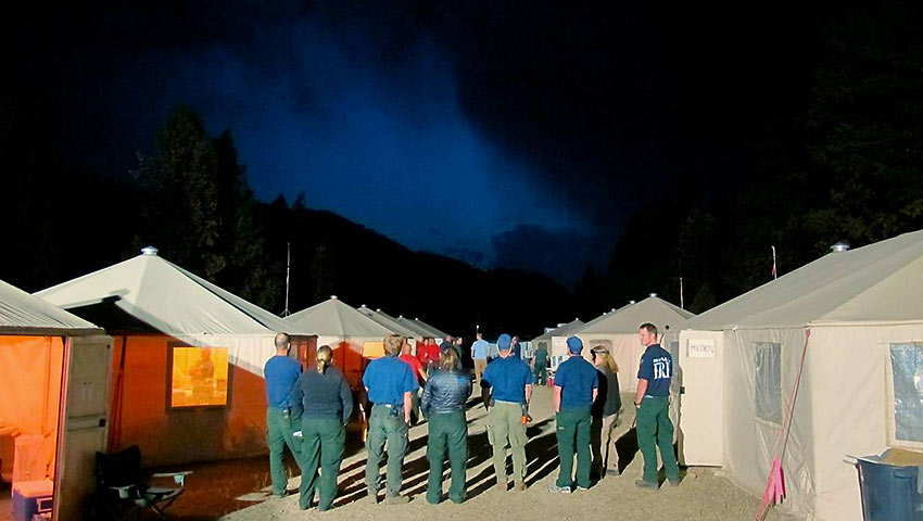 firefighters observe a thunderstorm from their camp