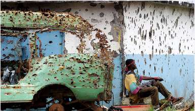 shrapnel-riddled vehicle and building in Liberia