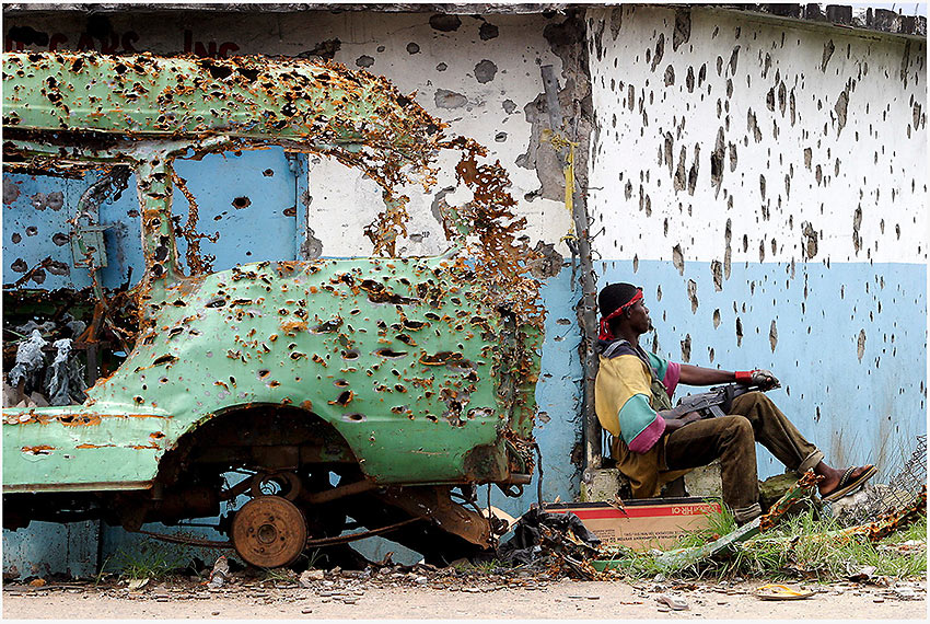 shrapnel-riddled vehicle and building in Liberia