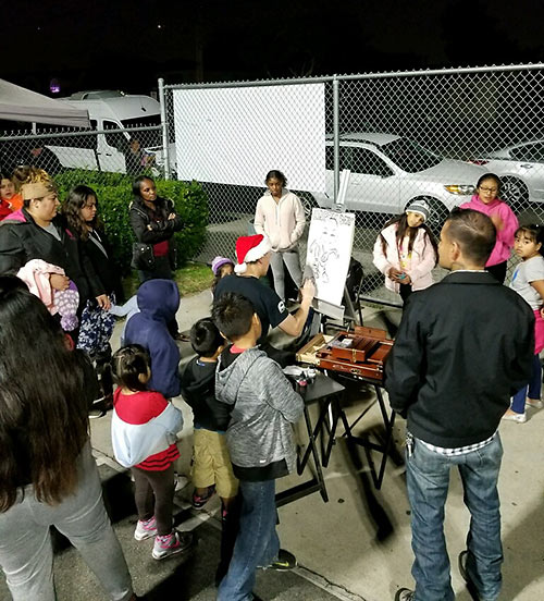 Raoul doing caricatures for families at Watts, Los Angeles