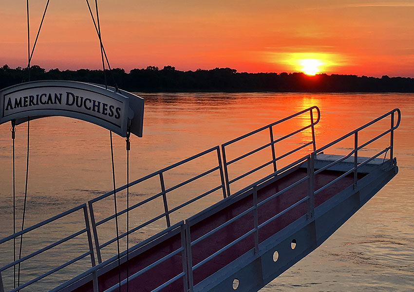 sunset on Mississippi River framed by a gangway on the American Duchess