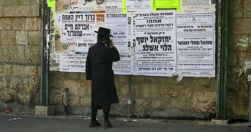 young Hasidic man reading posted news