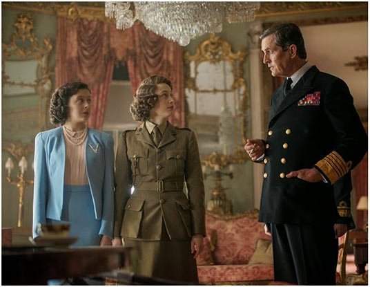 Princess Margaret Rose (Bel Powley) and Elizabeth (Sarah Gadon) receive instructions from their father, King George VI