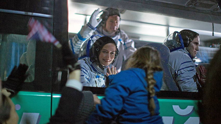 the flight crew gather behind a glass partition to say goodbye to their families