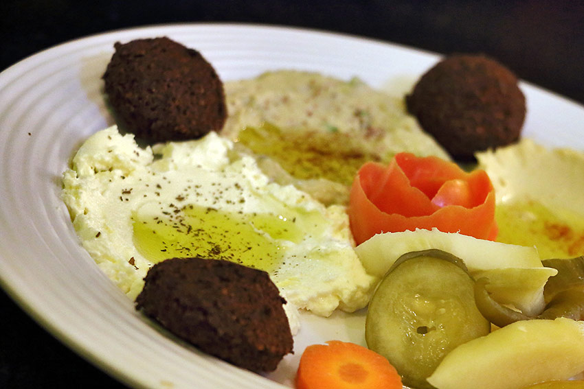 tzatziki dip served in a platter with hummus, moutabal and falafel balls
